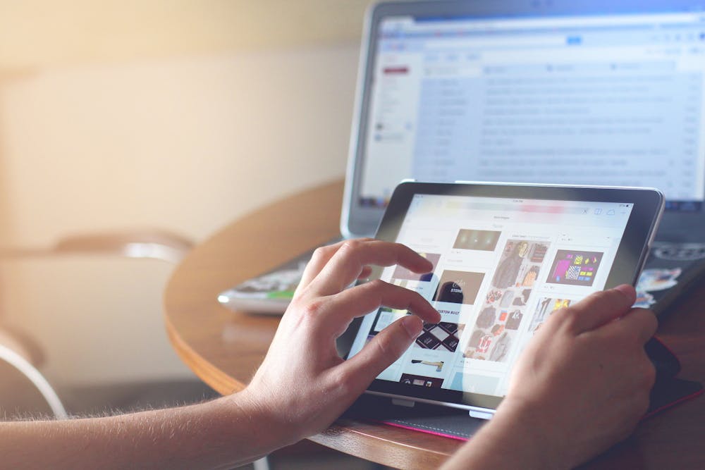 Image of person using tablet in front of laptop, depicting the requirement of tech skills for successful digital hr implementation