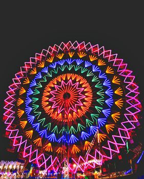 A mesmerizing Ferris wheel illuminated with vibrant neon lights against the night sky.
