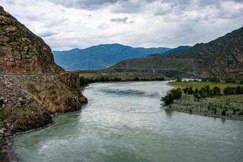 Free Tranquil river winding through rocky mountains under cloudy sky, perfect for nature lovers. Stock Photo
