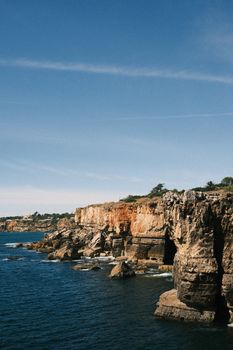 Dramatic cliff edges meeting the Atlantic Ocean near Lisbon, Portugal on a sunny day.