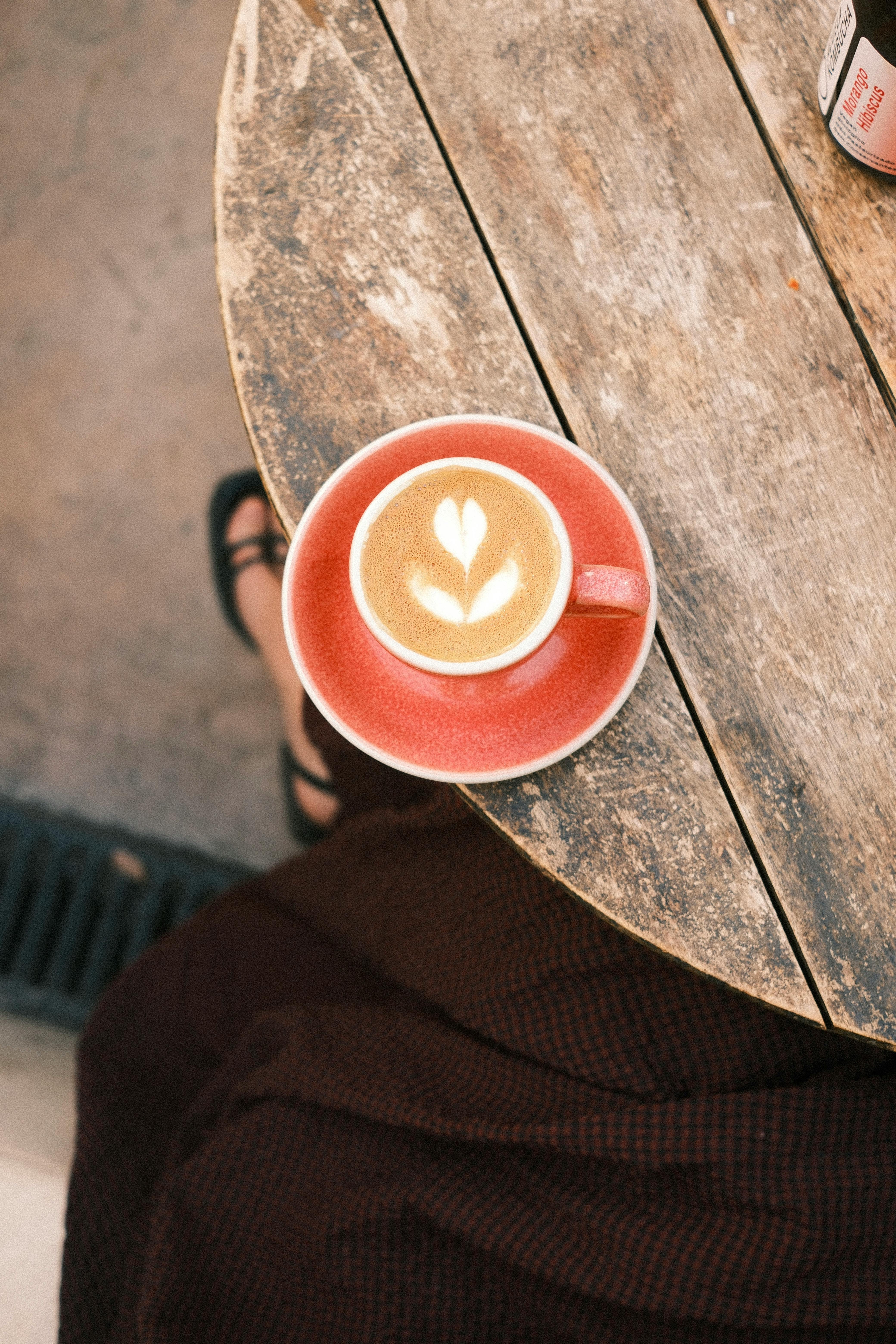 Gratuit Vue plongeante d'un cortado décoré d'un dessin en forme de cœur sur une table rustique, dans un café de Lisbonne. Photos