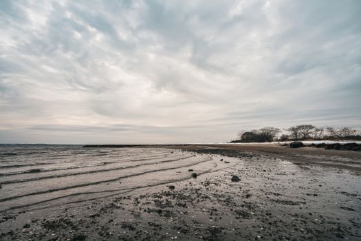 Serene beach scene at dusk with a cloudy sky and calm waves on the shore.