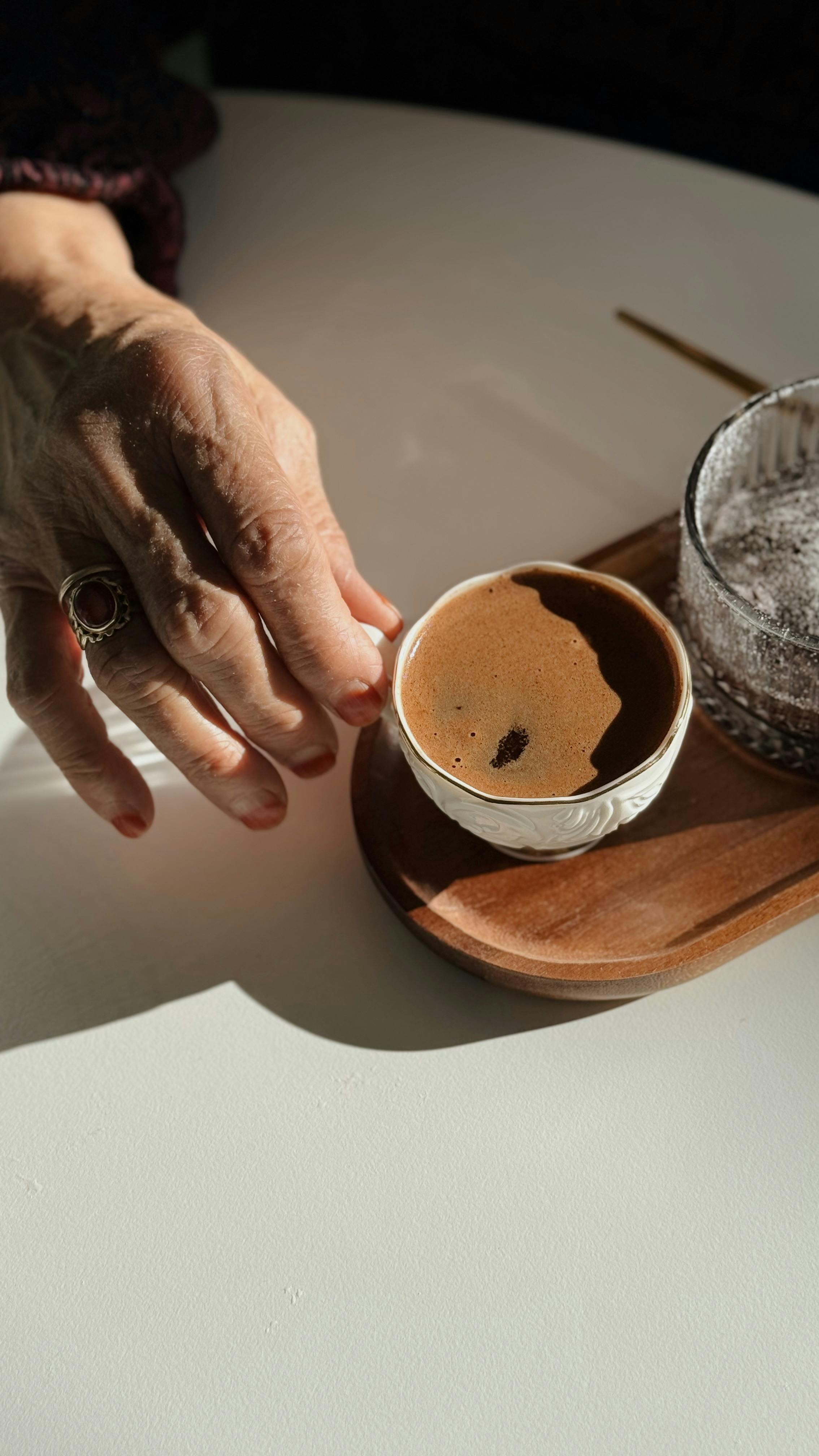 Gratuit Une main portant une bague tient une tasse de café turc sur un plateau en bois. Photos