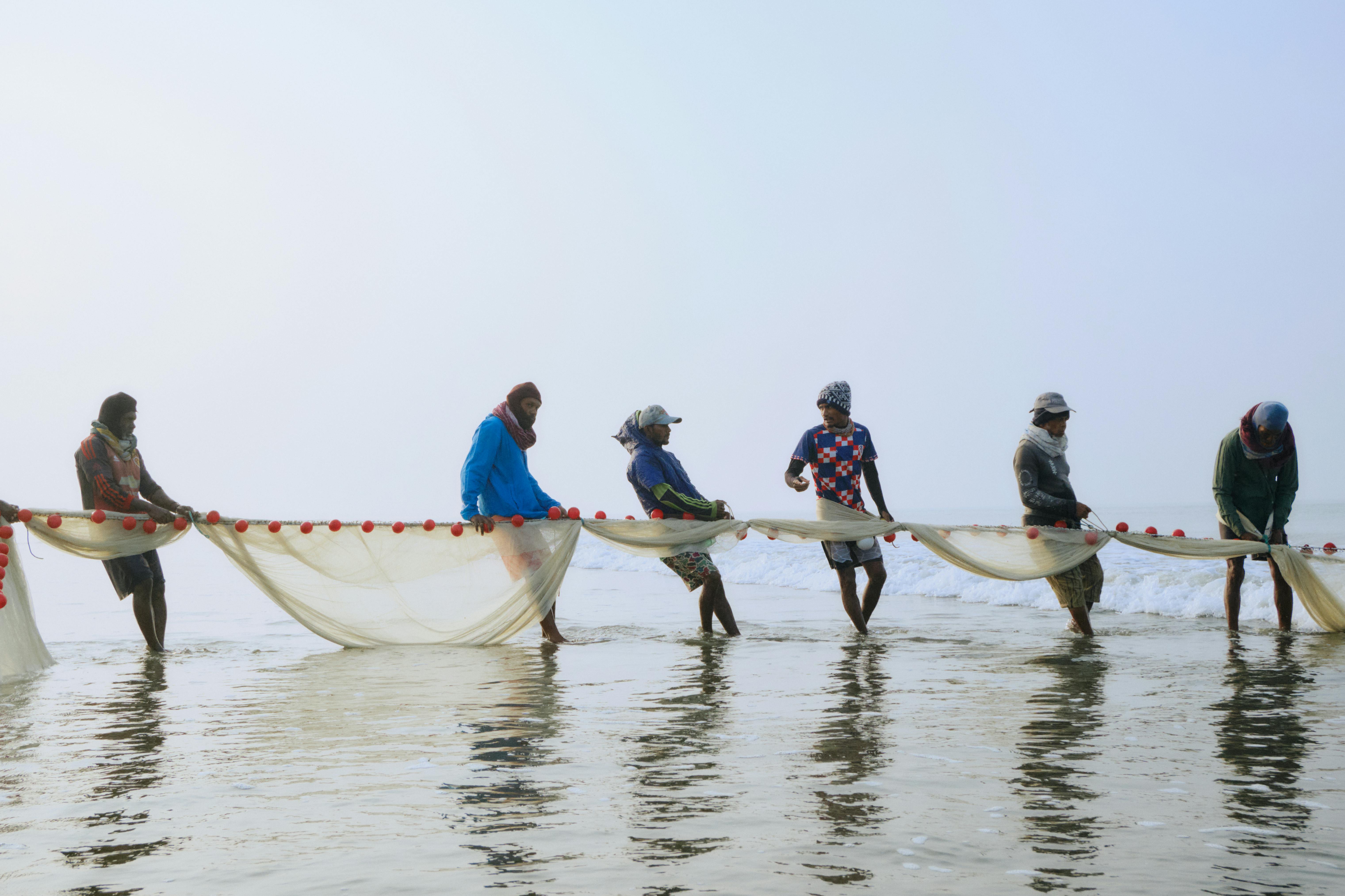Gratuit Des pêcheurs remontent leurs filets sur la plage de Cox's Bazar, immortalisant une scène matinale sereine au Bangladesh. Photos