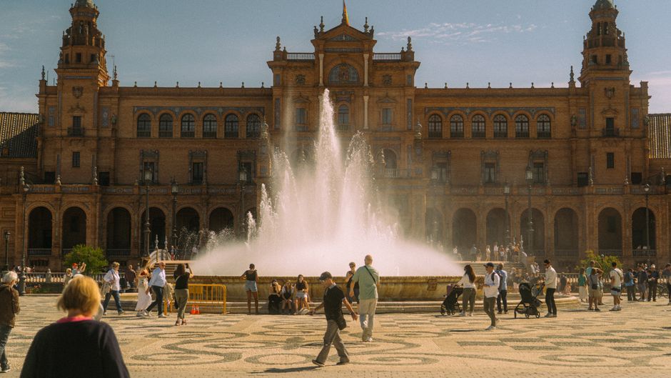 Gente disfrutando de la vista en la Plaza de España, Sevilla, junto a la fuente.