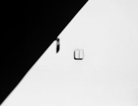 A minimalist photo of a light switch with contrasting black and white tones, creating a geometric abstract composition.