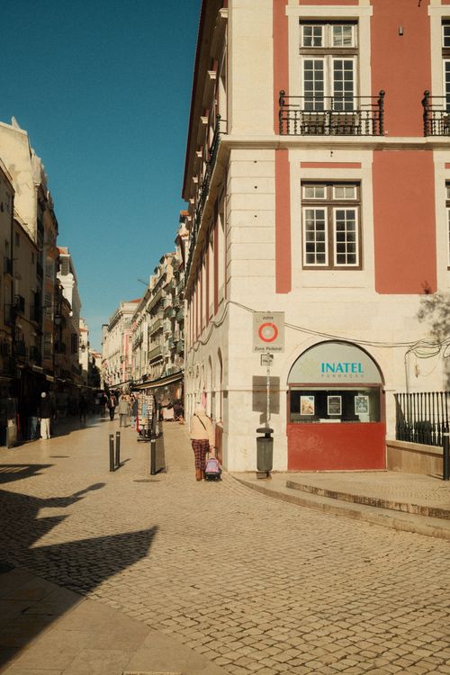 Free Idyllic view of a sunlit street in Lisbon, showcasing traditional architecture and vibrant life. Stock Photo