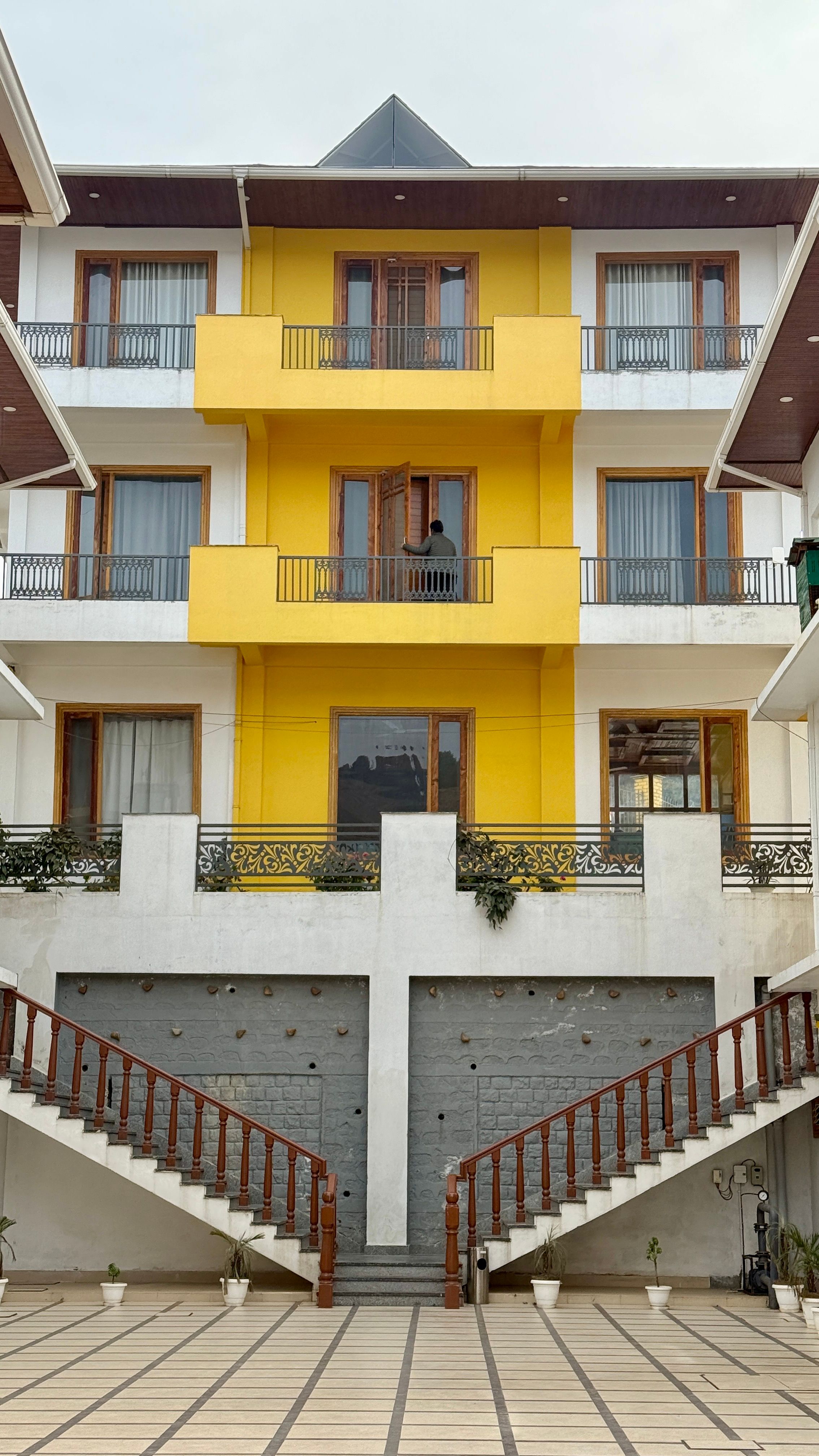 Bright yellow facade of a modern residential building with symmetrical balconies.