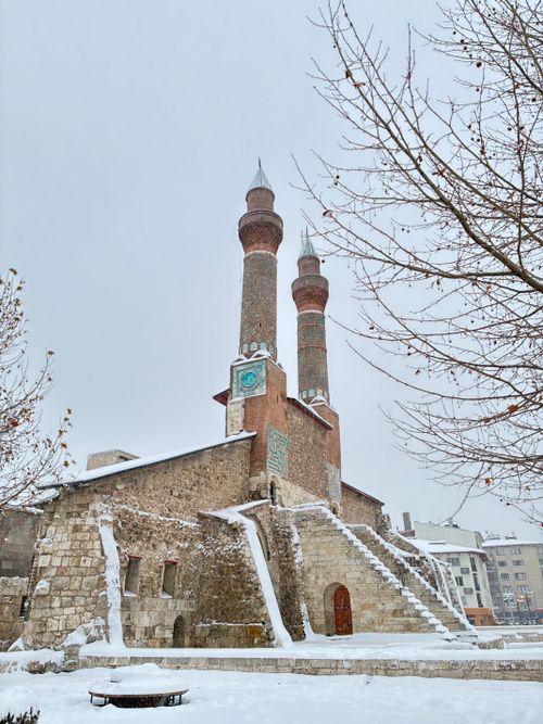 Free A serene winter view of the historic Twin Minaret Madrasa in Sivas, Türkiye, covered in snow. Stock Photo