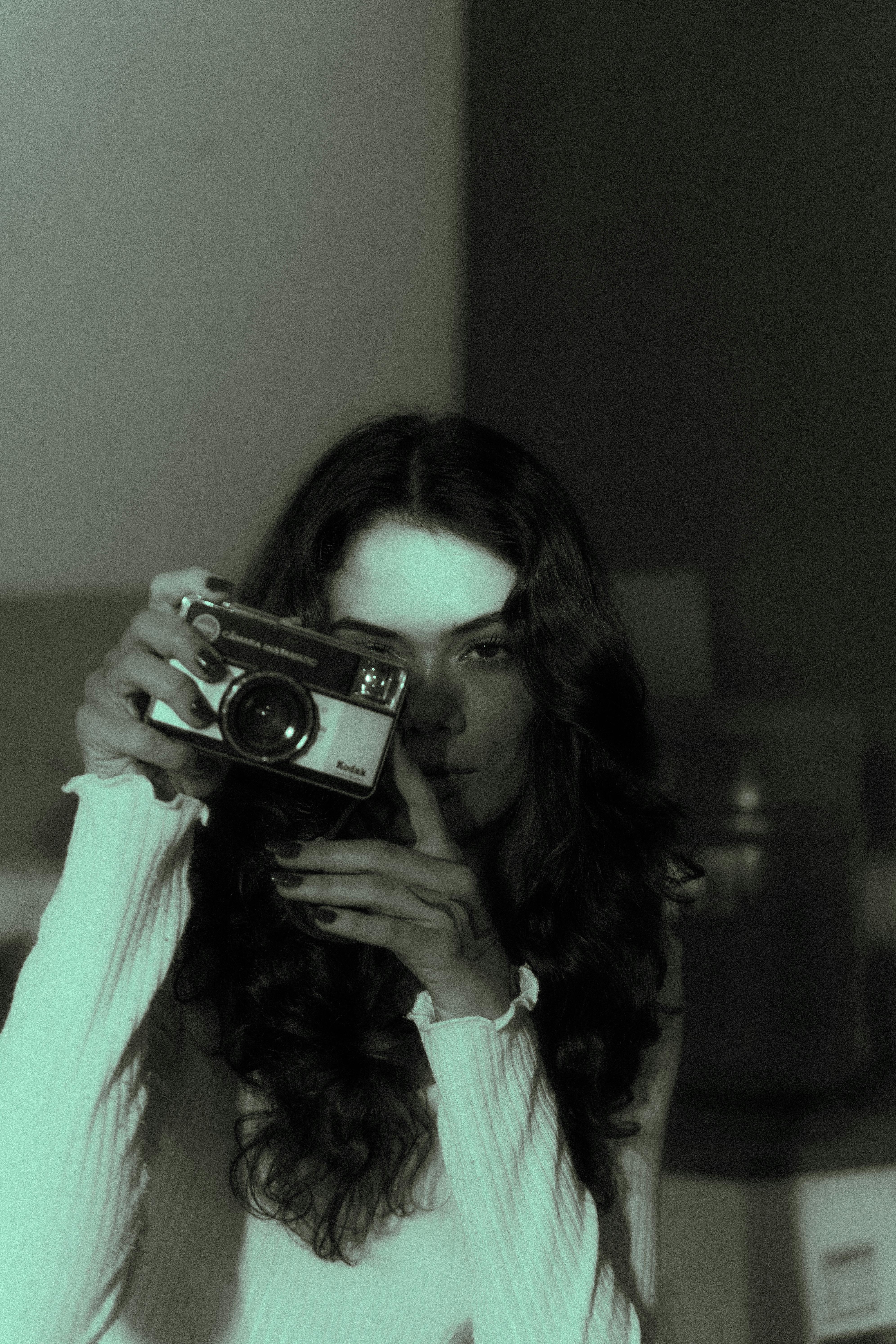 gratis Sfeervol portret van een vrouw die binnenshuis een vintage filmcamera vasthoudt. Stockfoto