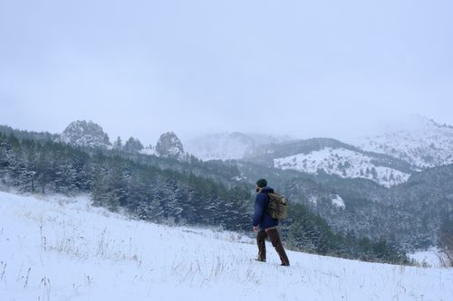 Free A lone hiker explores a snowy mountain landscape under a cloudy sky. Stock Photo