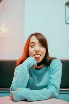 一位穿着蓝色毛衣的年轻女子在室内俏皮地吐了吐舌头