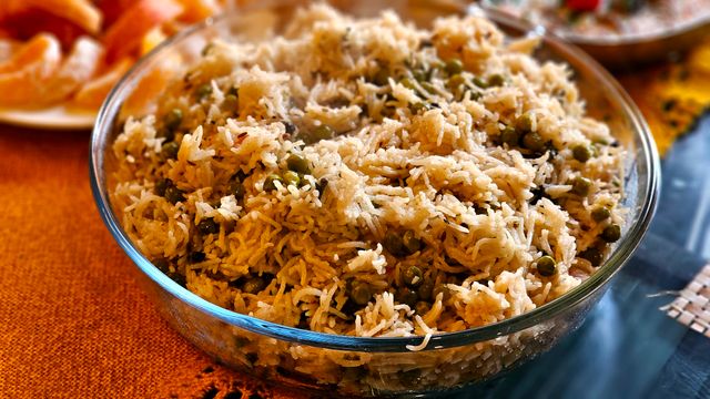 Mouthwatering pea pulao served hot in a transparent glass bowl, perfect for any meal.
