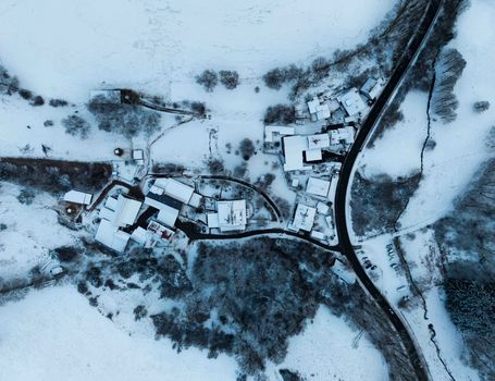Stunning aerial view of a snow-covered village surrounded by wintry wilderness.