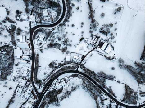 Stunning aerial view of a winding road through a snow-covered rural landscape during winter in Germany.