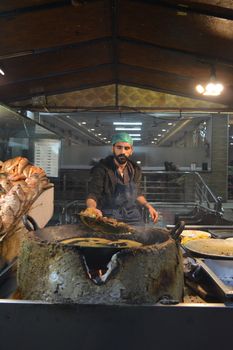 Street vendor frying fish at an indoor market in Hassanabad, Punjab, Pakistan.