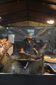 A vendor prepares fresh seafood at a bustling night market in Hassanabad, showcasing traditional cooking techniques.
