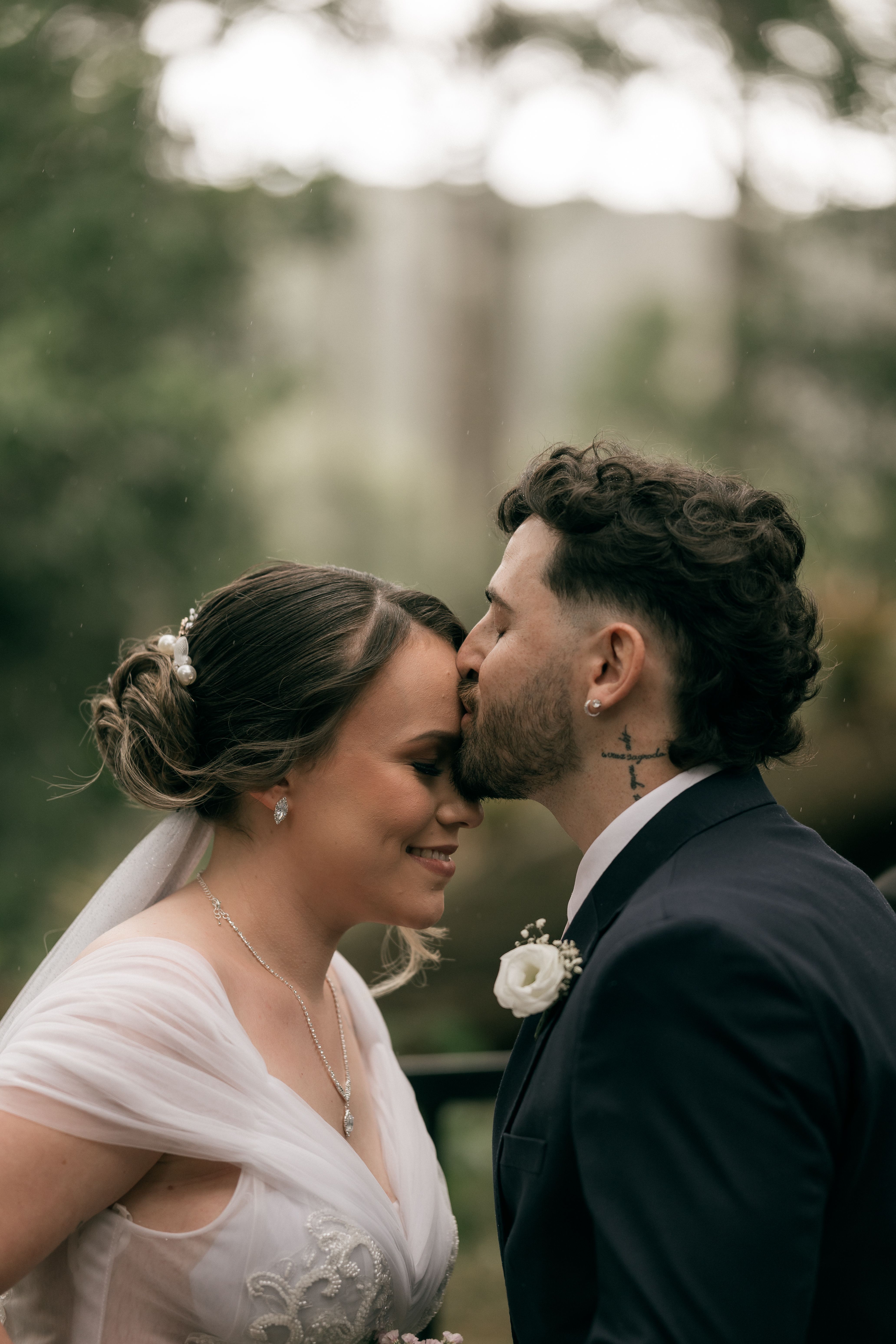 A romantic moment captured at an outdoor wedding with a couple sharing a tender kiss.