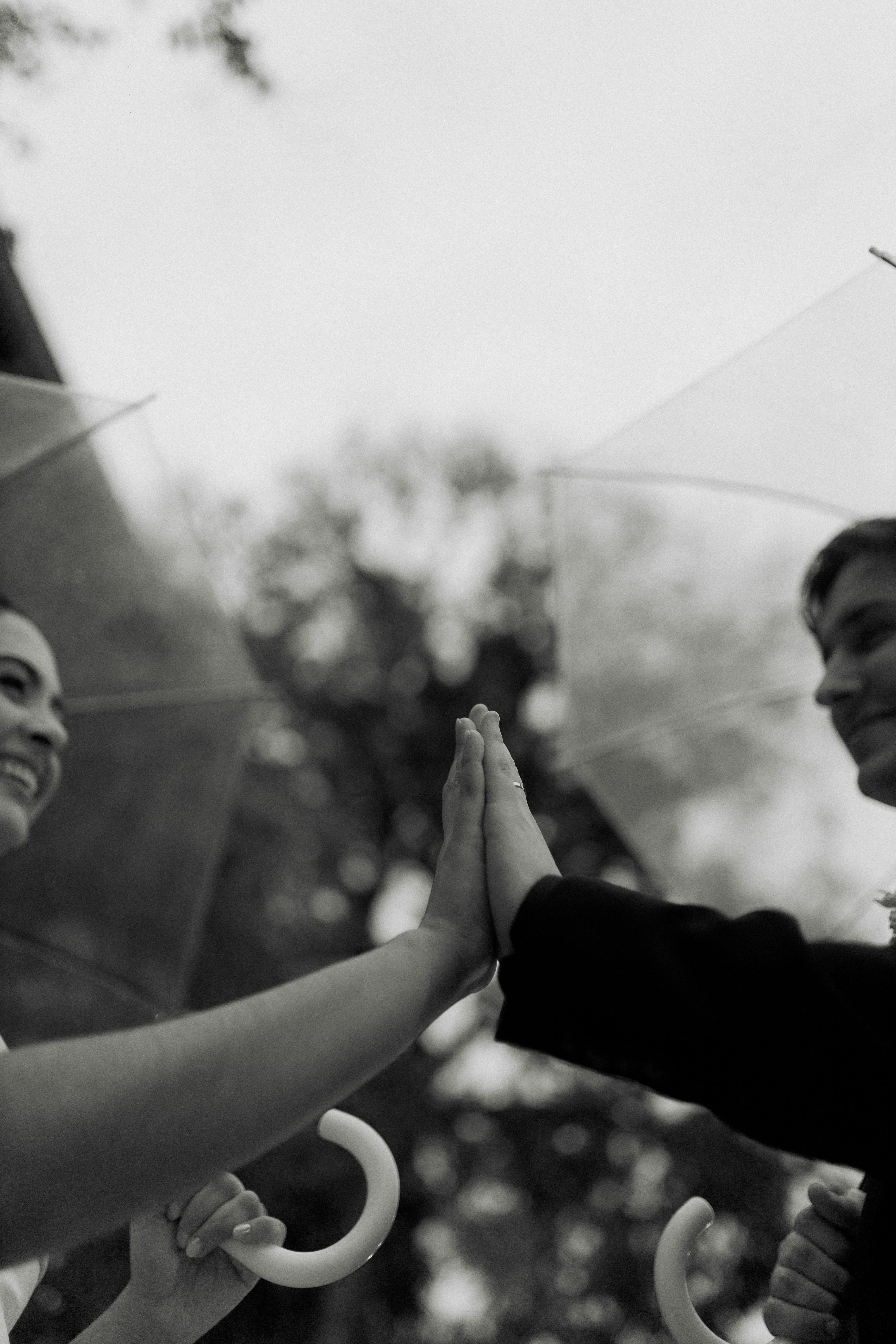 Gratis Representación artística en blanco y negro de una amistad entre dos personas chocando los cinco bajo paraguas. Foto de stock