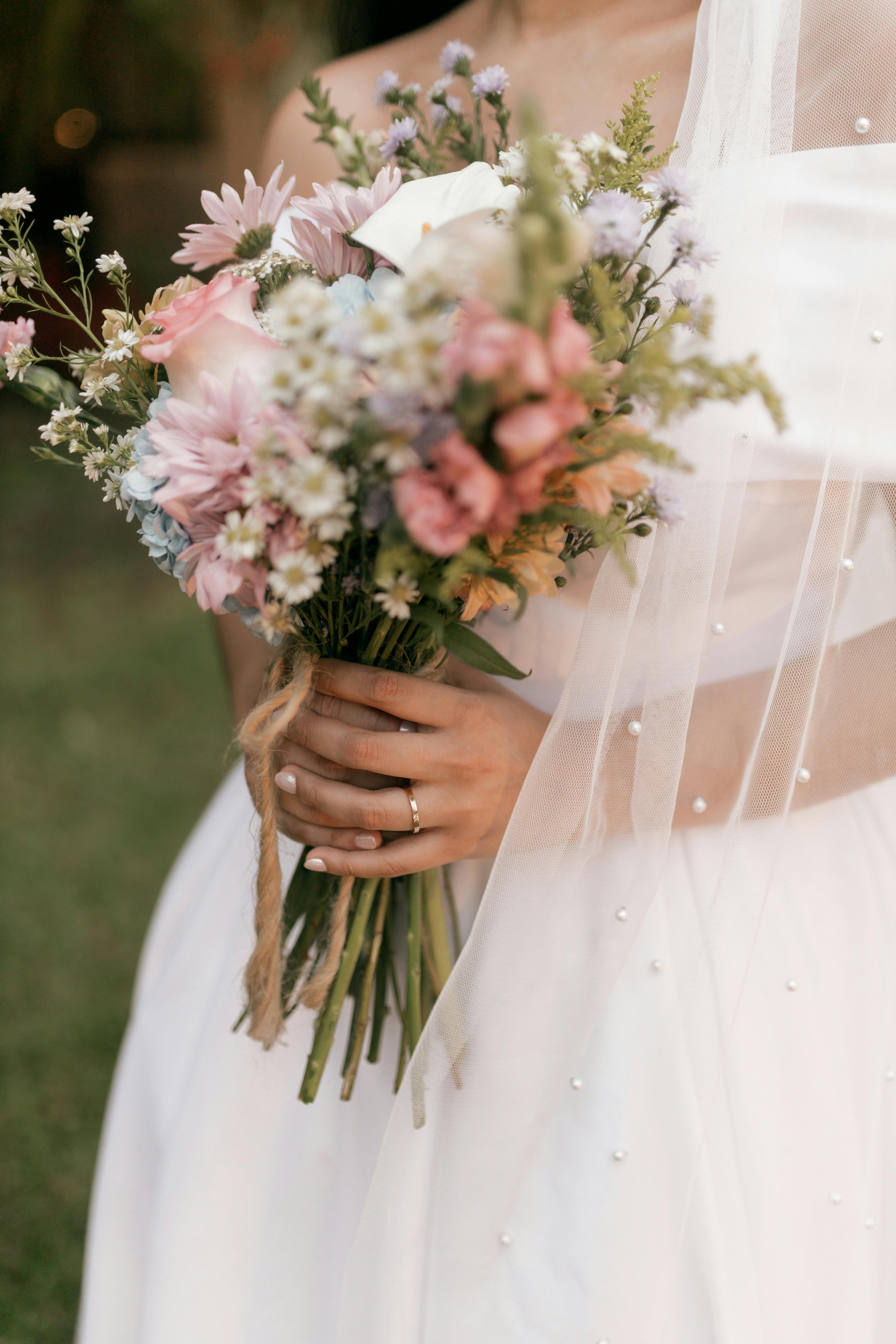 Gratuit Une élégante mariée tenant un magnifique bouquet de fleurs aux teintes pastel le jour de son mariage, en extérieur. Photos