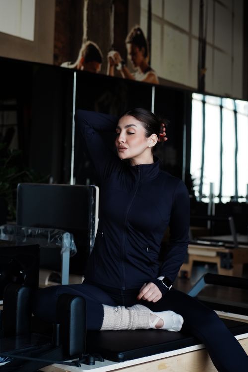 Free A woman practicing yoga indoors on a Pilates machine wearing workout clothes. Stock Photo
