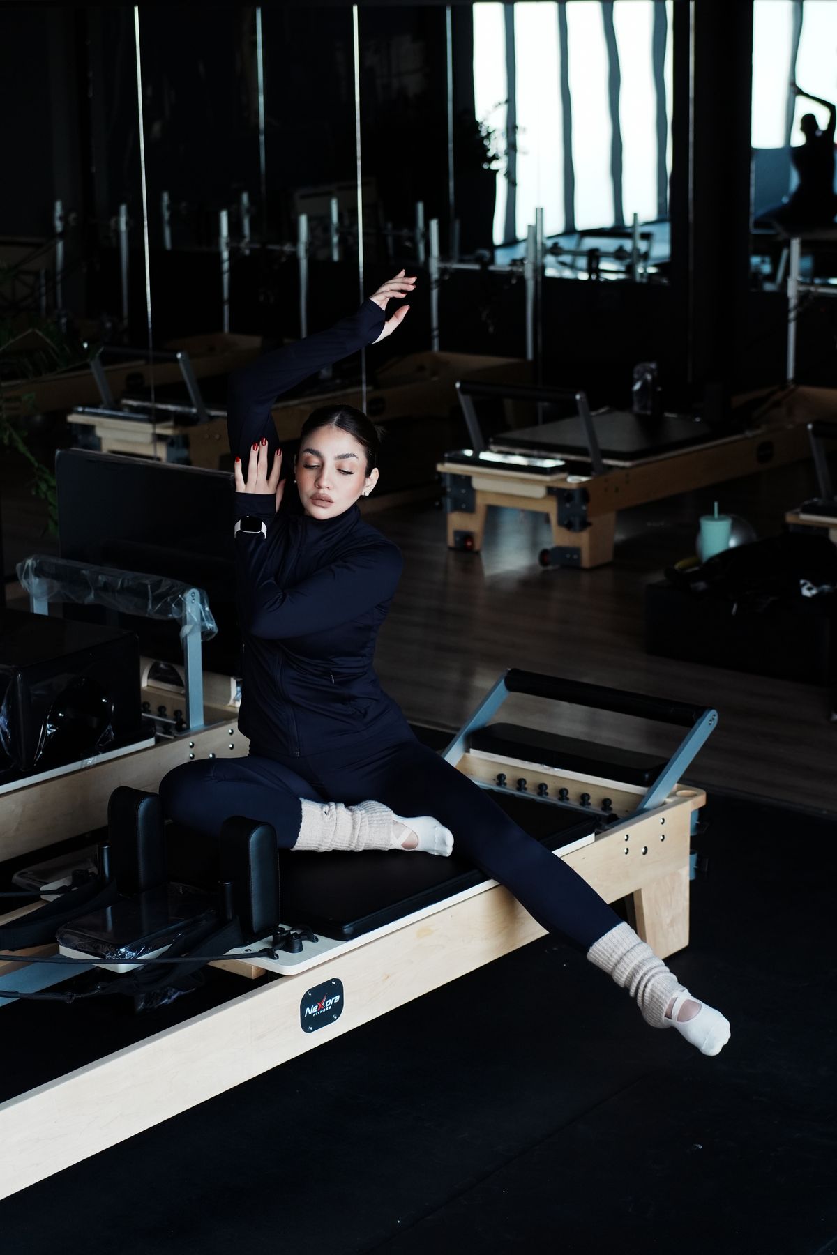 Woman stretching on a Pilates reformer machine