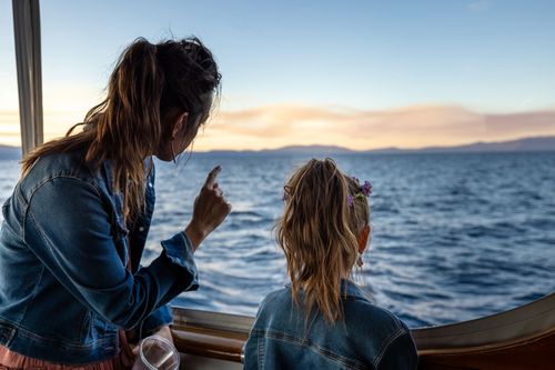 Free A mother and daughter share a moment while enjoying a scenic boat ride at sunset. Stock Photo