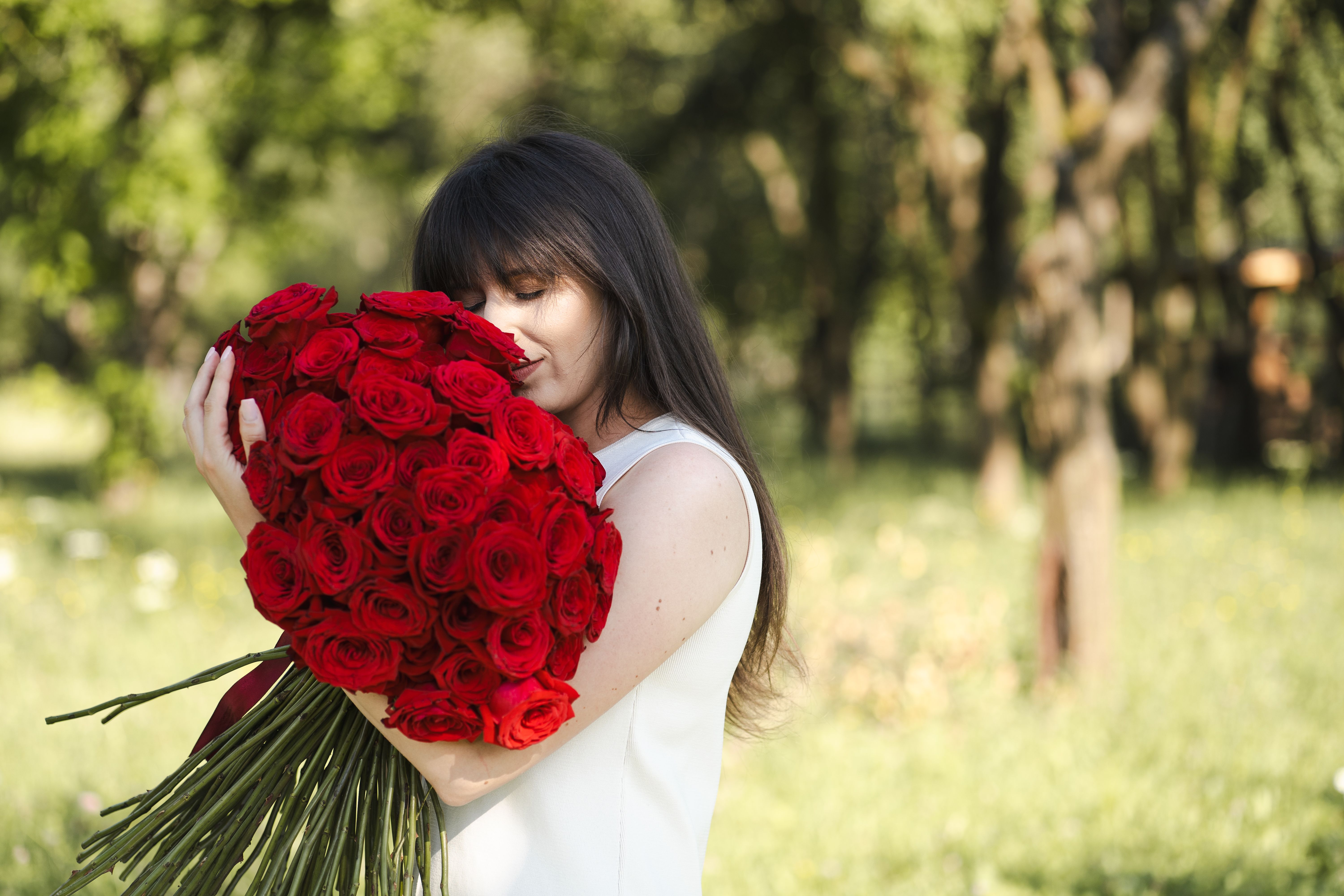 Woman Embracing Bouquet of Red Roses Outdoors · Free Stock Photo