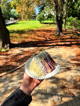 A slice of cake with berry filling on a sunny autumn day in a park, perfect for fall picnics.