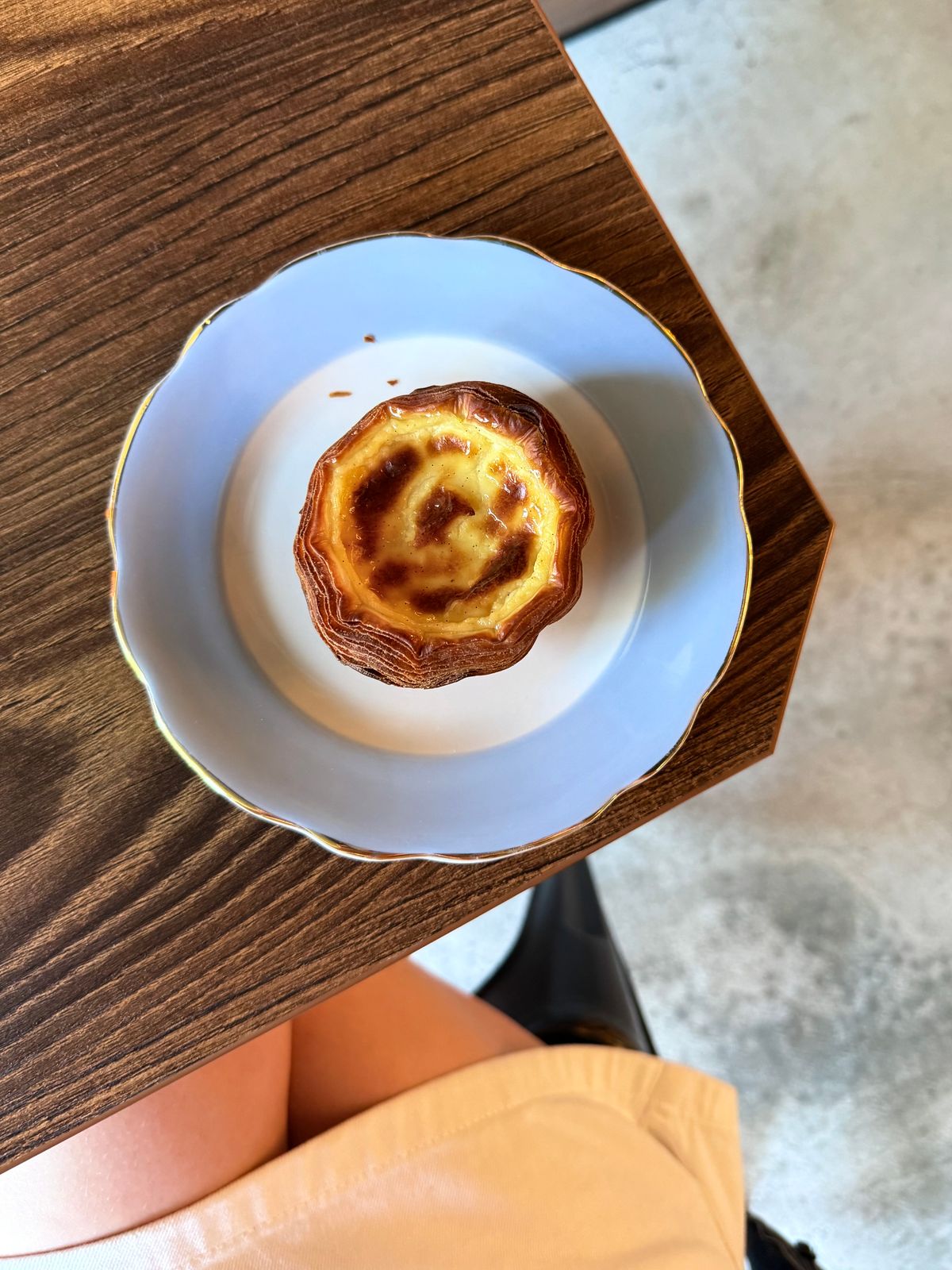 A perfectly baked Portuguese-style egg custard tart on a blue-rimmed plate