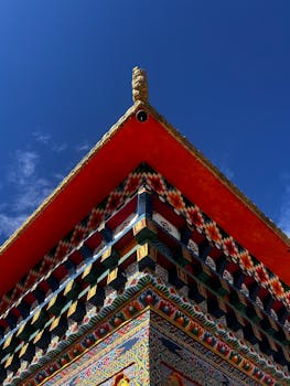 Colorful roof of a Buddhist temple in Mechuka, showcasing intricate patterns and bright hues against a clear sky.
