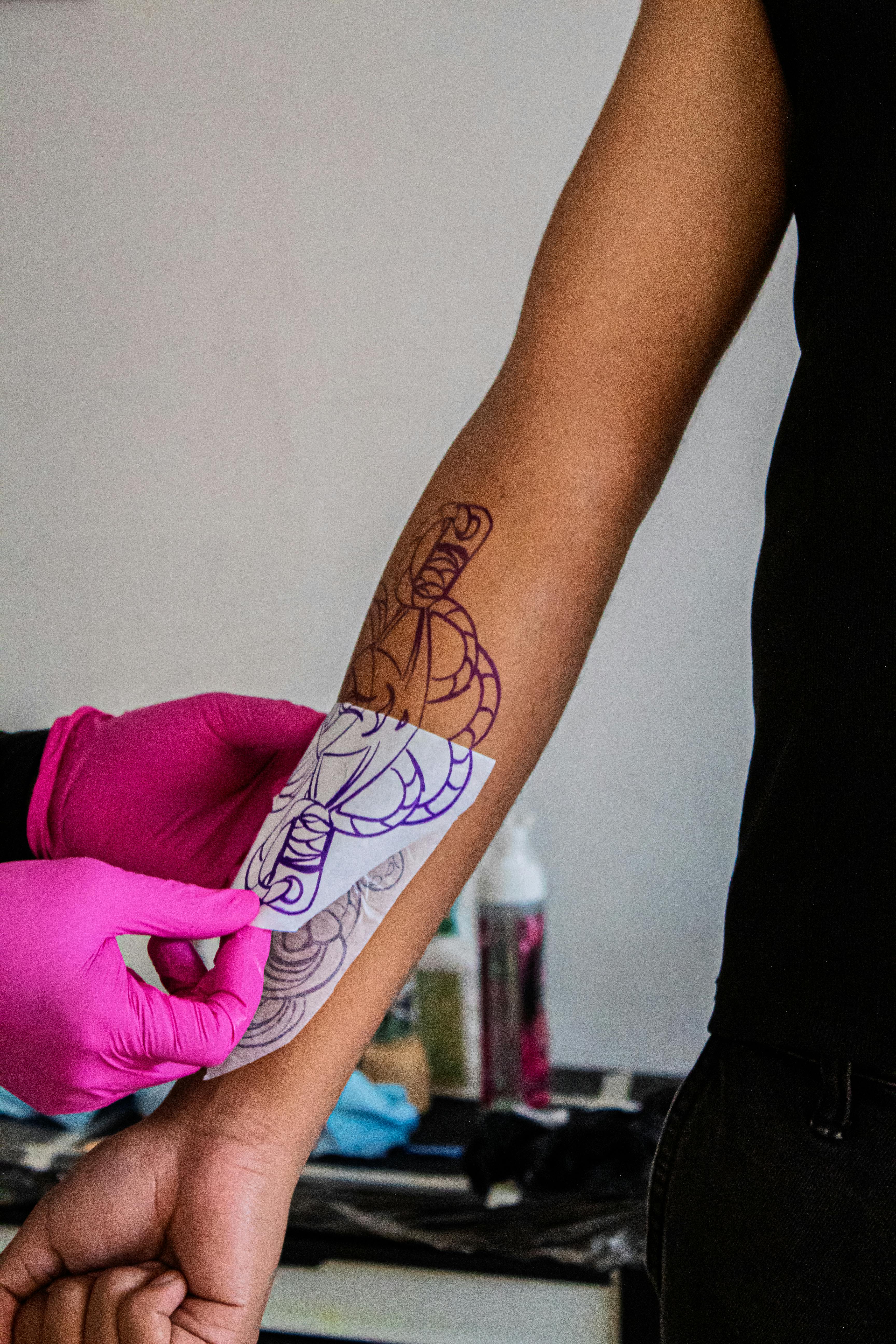 Artist đặt stencil lên tay khách trước khi xăm
