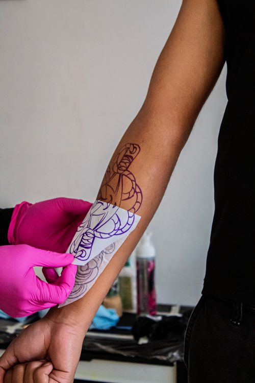 Artist đặt stencil lên tay khách trước khi xăm