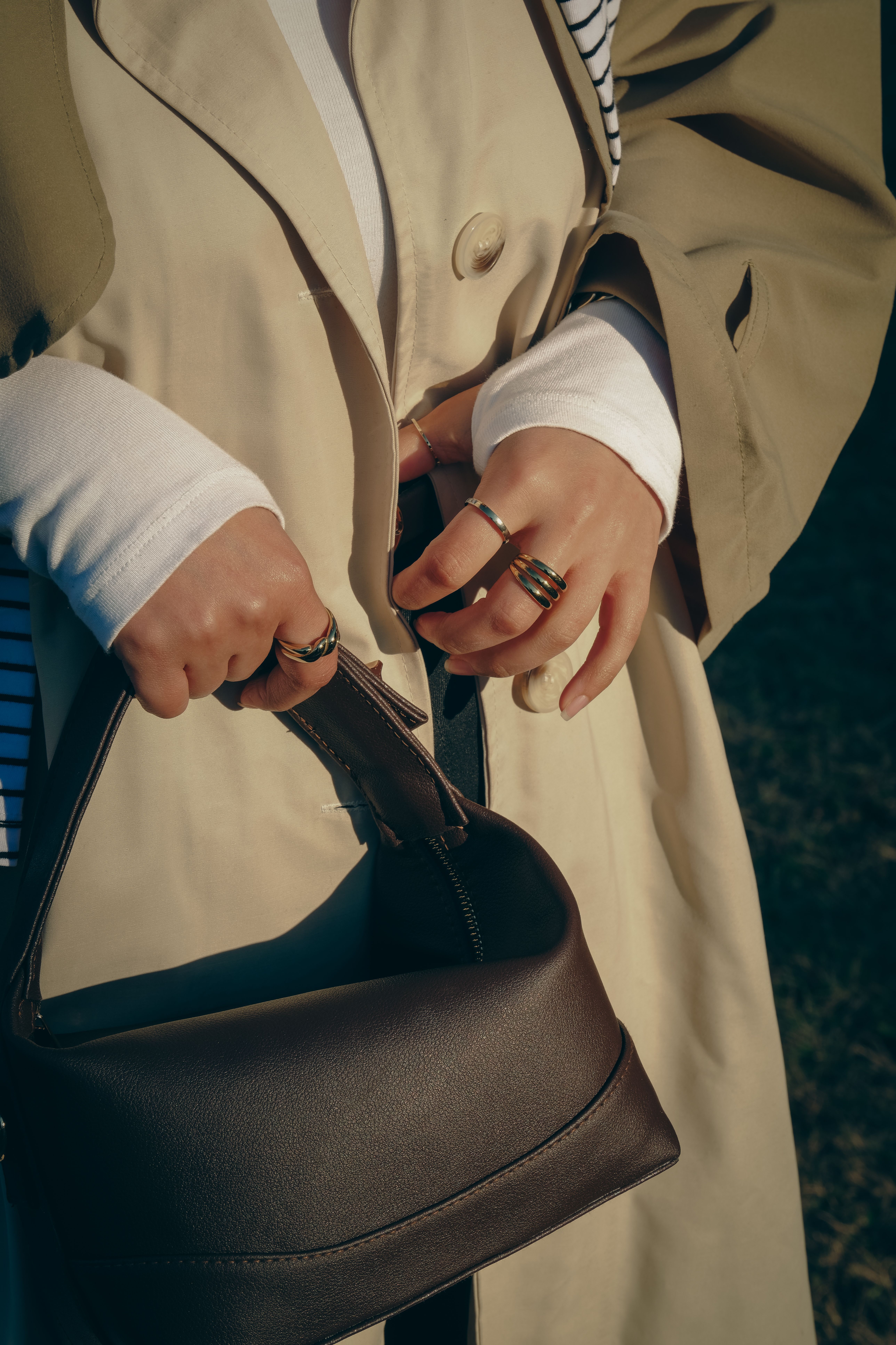 Close-up of a stylish woman holding a brown leather handbag, showcasing jewelry, in Gaziantep.