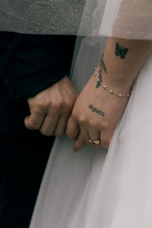 Free Close-up of a bride and groom holding hands, showcasing wedding rings and tattoos. Stock Photo