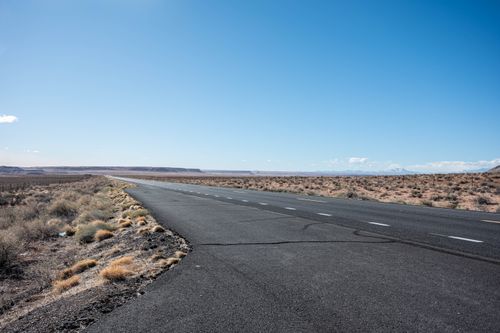 Free An expansive desert highway with clear skies and arid landscape, showcasing solitude. Stock Photo