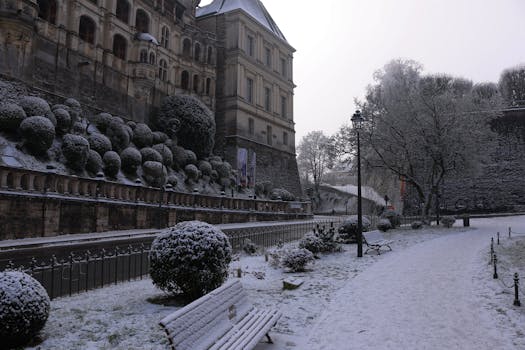 A serene winter scene showcasing a historic building and snowy park path.