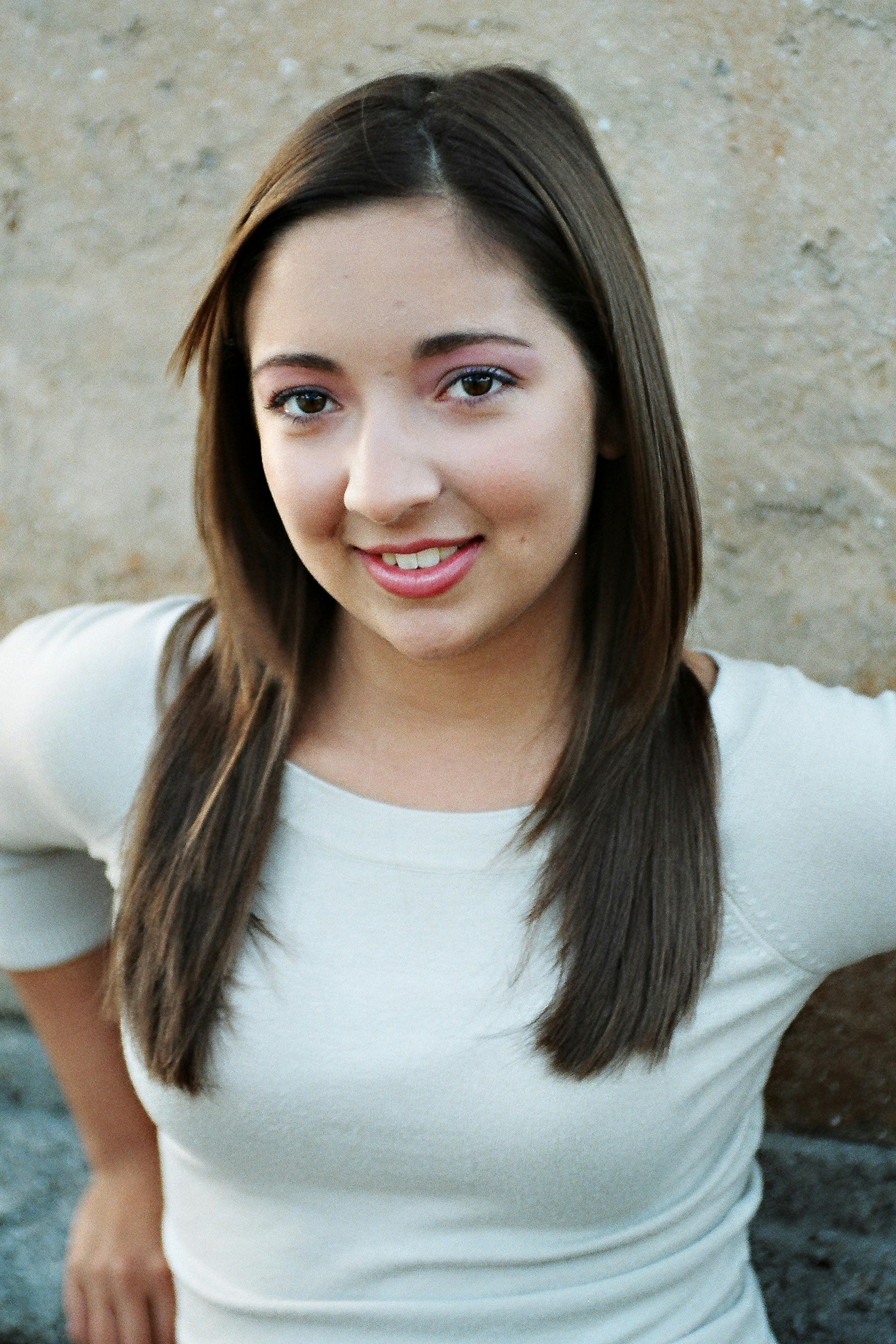 Kostnadsfria En ung kvinna poserar avslappnat utomhus mot en strukturerad vägg. Stock foto