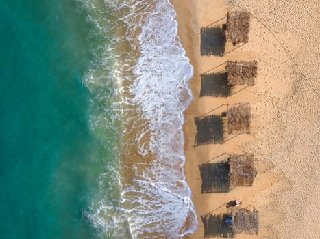 Aerial shot of beach huts along the coastline in Trancoso, Bahia, Brazil, with turquoise waves.
