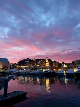 A vibrant sunset over the marina in Cabo San Lucas, showcasing boats and colorful skies.