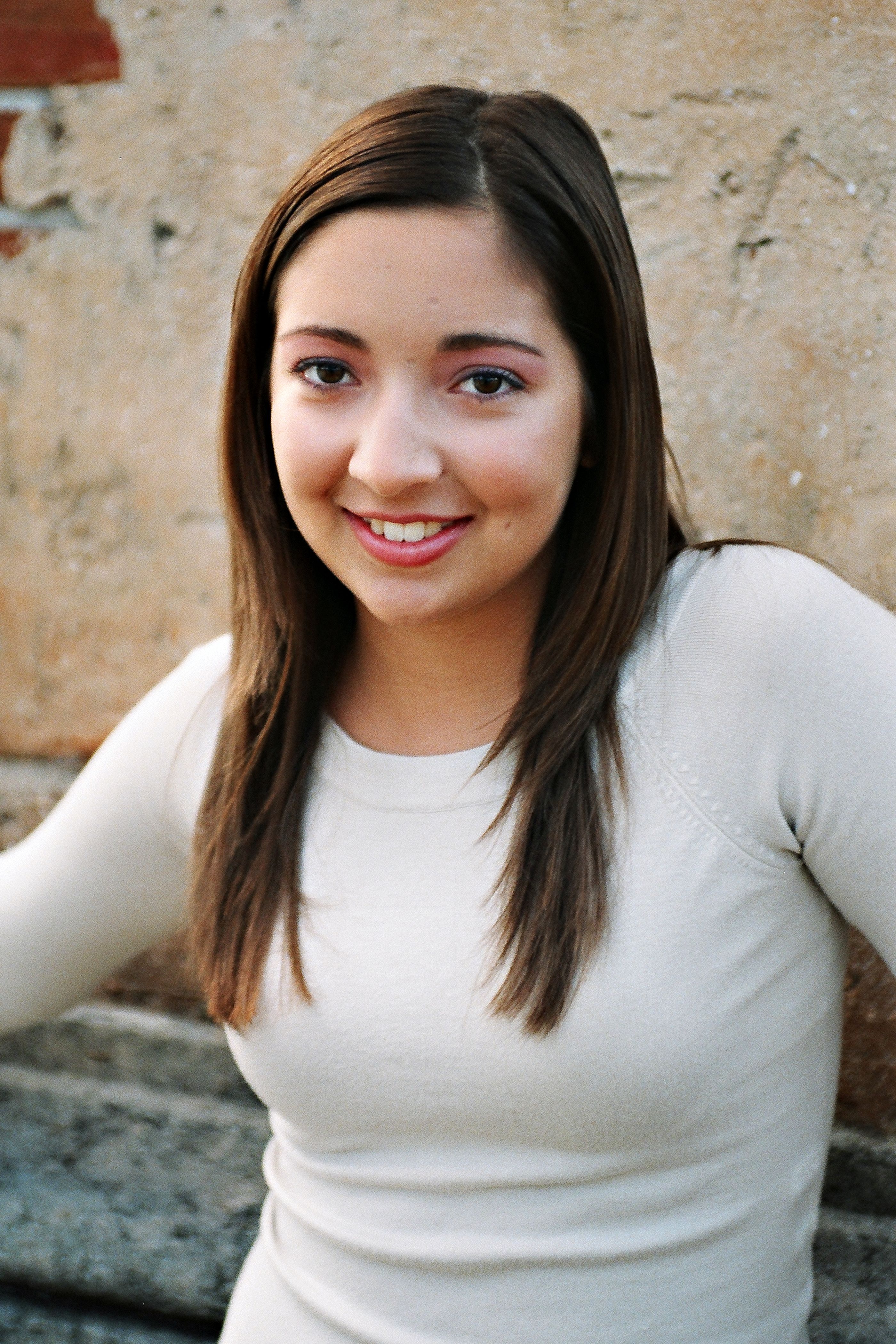 Portrait of a young woman with a smile standing by an aged wall