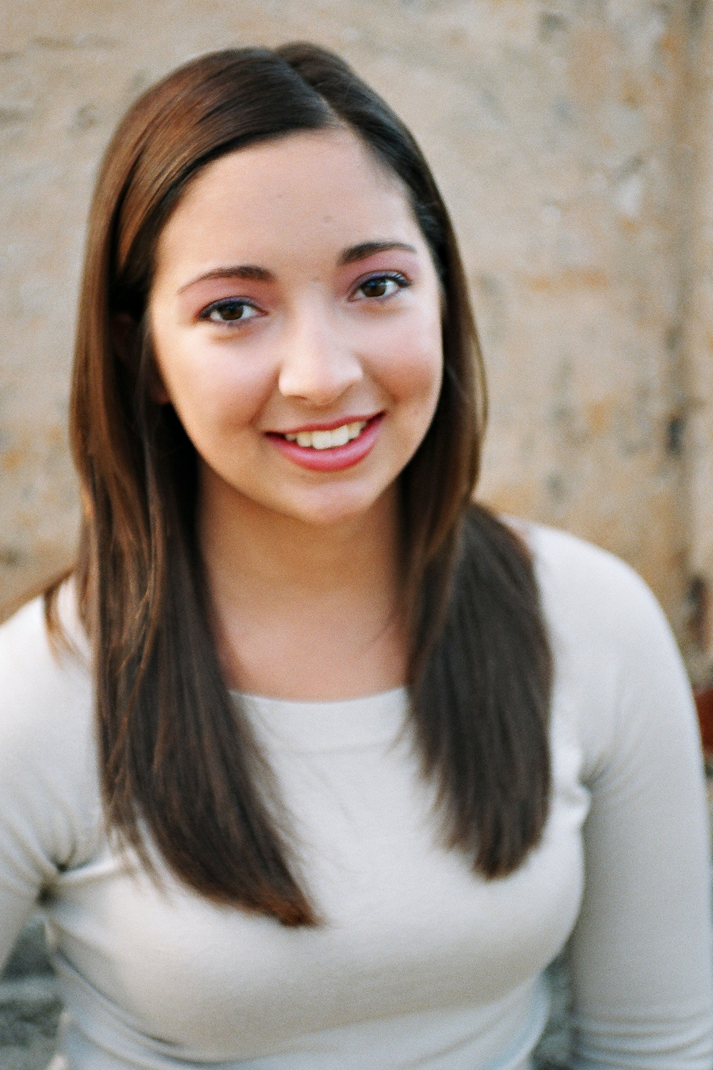 Portrait of a smiling young woman against a textured wall background.