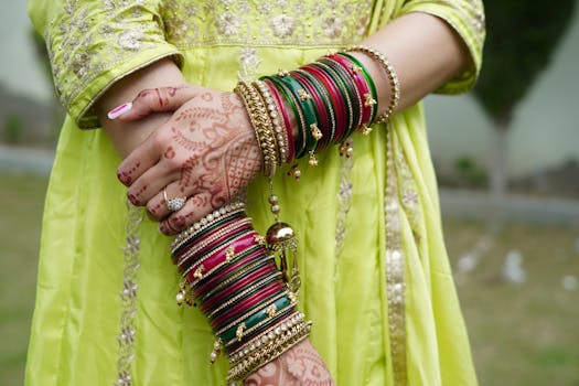 Detailed view of vibrant bangles and intricate henna on a woman's arms wearing a traditional dress.