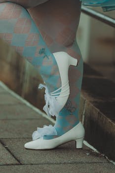 Elegant legs adorned with blue fishnet stockings and white heels showcase modern fashion and style.
