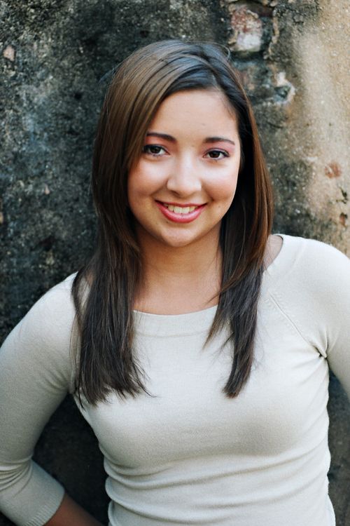 Free Smiling young woman leaning against rustic wall portrait. Stock Photo