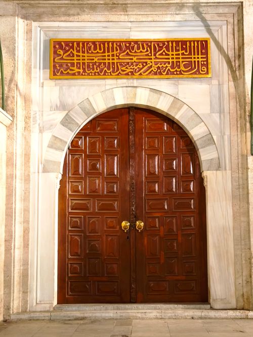 Free Elegant wooden door with Arabic calligraphy sign, in an archway setting. Stock Photo