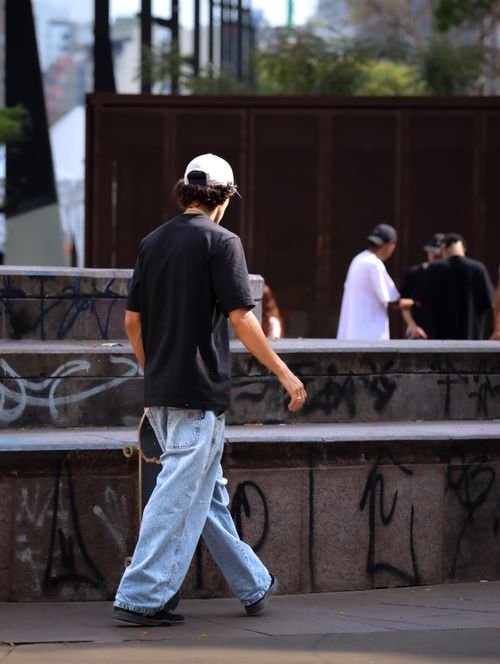 Free A man in casual streetwear walks in an urban area with graffiti. Stock Photo