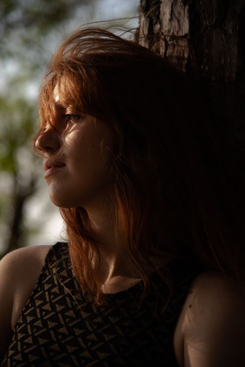 Free A serene portrait of a red-haired woman enjoying the sunlight outdoors in Estonia. Stock Photo