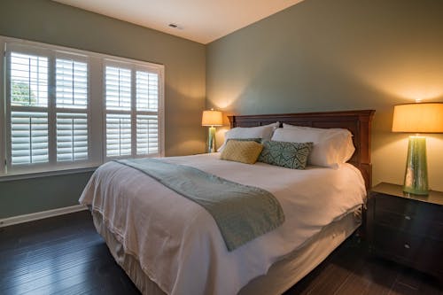 Bed Near Window Blinds and Lighted Desk Lamps