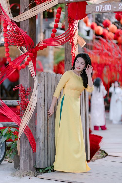 Free Young woman in yellow dress amidst vibrant red festival decorations outdoors. Stock Photo